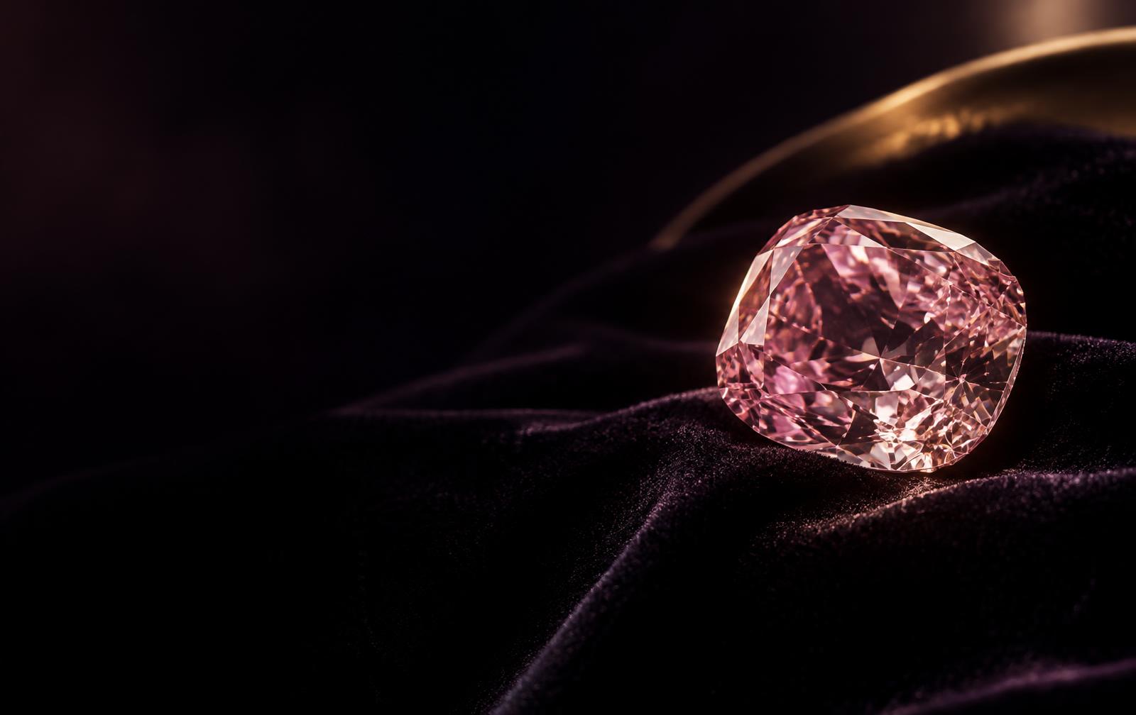 A natural pink diamond resting on black velvet